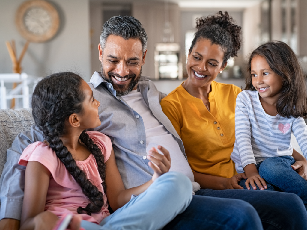 A family laughing and connecting together on a couch in warm light